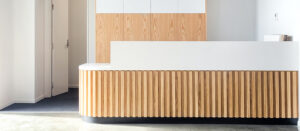 Entrance area of a health space featuring wooden counter panelling and concrete flooring.