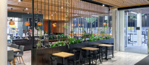 Tables and chairs with timber ceiling feature and plant boxes in new cafe fitout